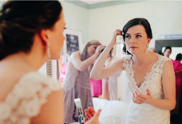 Bride touching up her hair in the bathroom mirror before ceremony
