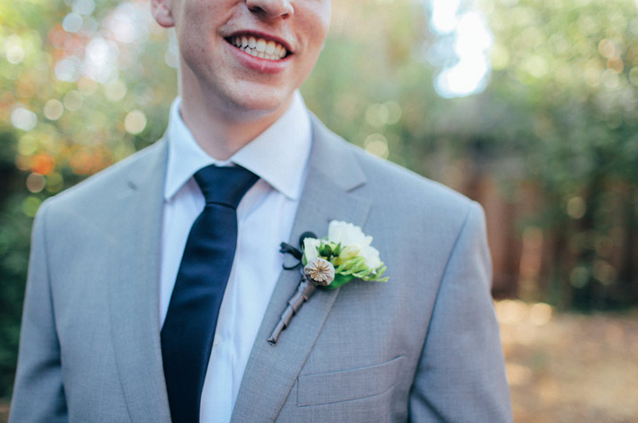 close up of groom's corsage with groom smiling big