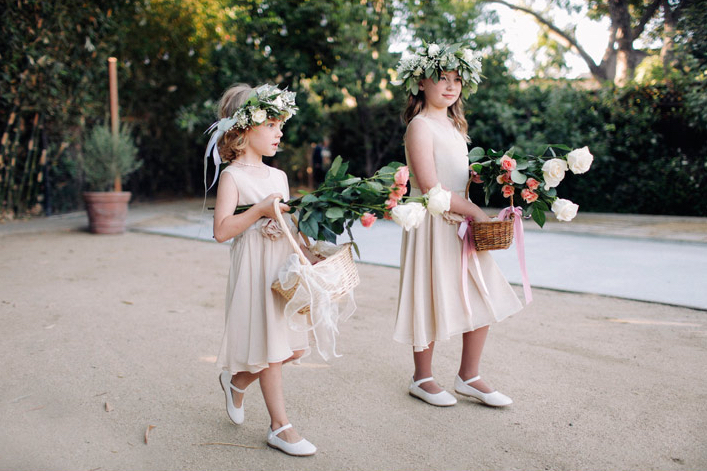 flower girls with flower crowns and baskets walking down the aisle